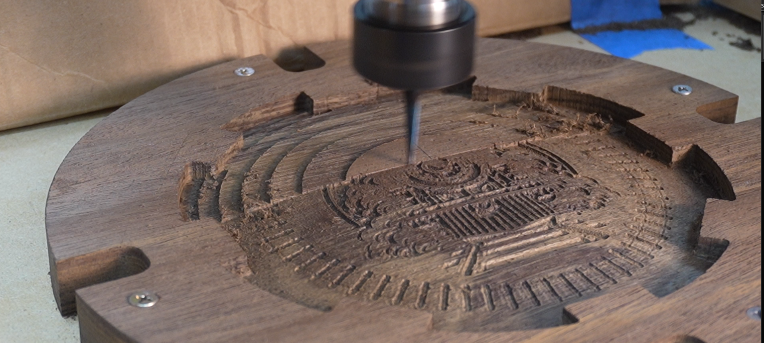 Close-up of Fusion Pro CNC machine carving intricate train details into a wooden Mexican Train domino game piece using a 0.5mm tapered ball nose engraving bit, showing fine 3D relief carving in walnut
