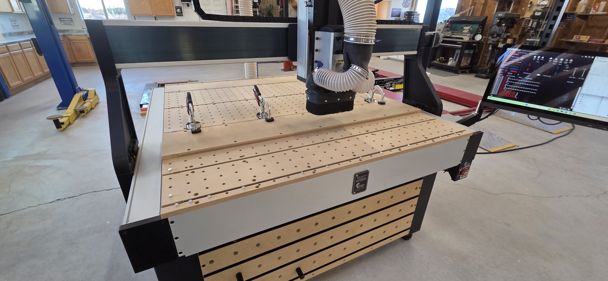Fusion Pro CNC 50x50 installed in a professional workshop showing spoilboard, clamps, gantry, and dust collection